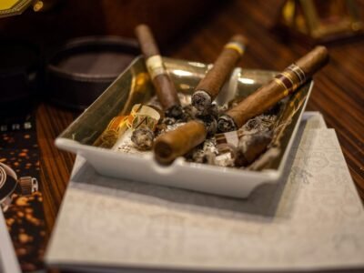 A detailed view of cigars resting in an ashtray on a wooden table, showcasing a smoking ambiance.